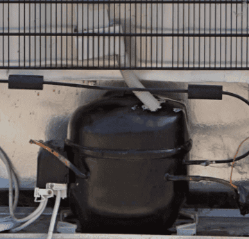 Fridge compressor shown installed with rear panel removed