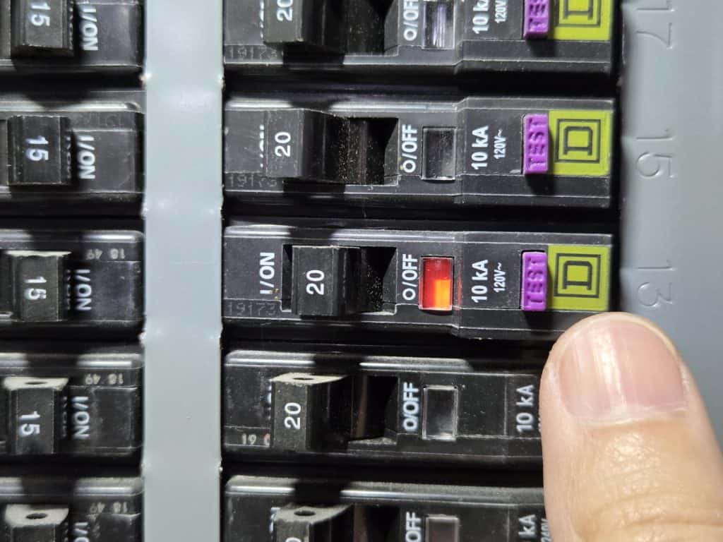 Tripped GFCI breaker showing orange indicator and handle in center position