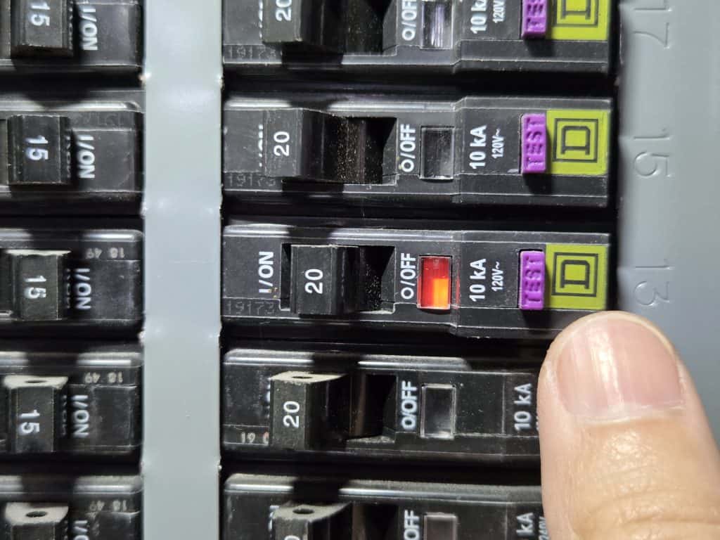 Breaker is in tripped state, as shown by the handle in half-way position and orange indicator